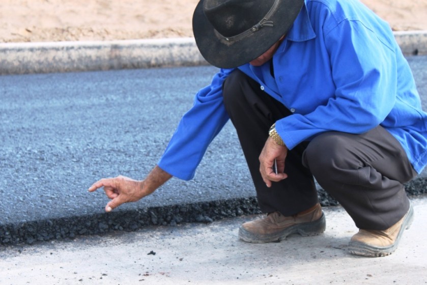 O encarregado mostra a camada de asfalto que será acrescida àquela que está sendo feita agora.