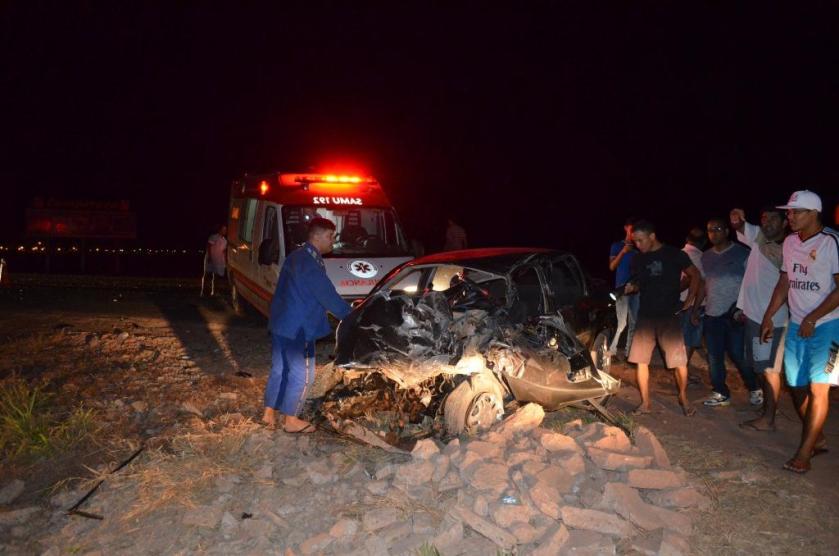 O carro teve a dianteira destruída na colisão. A porta abriu e o motorista caiu sobre o acostamento
